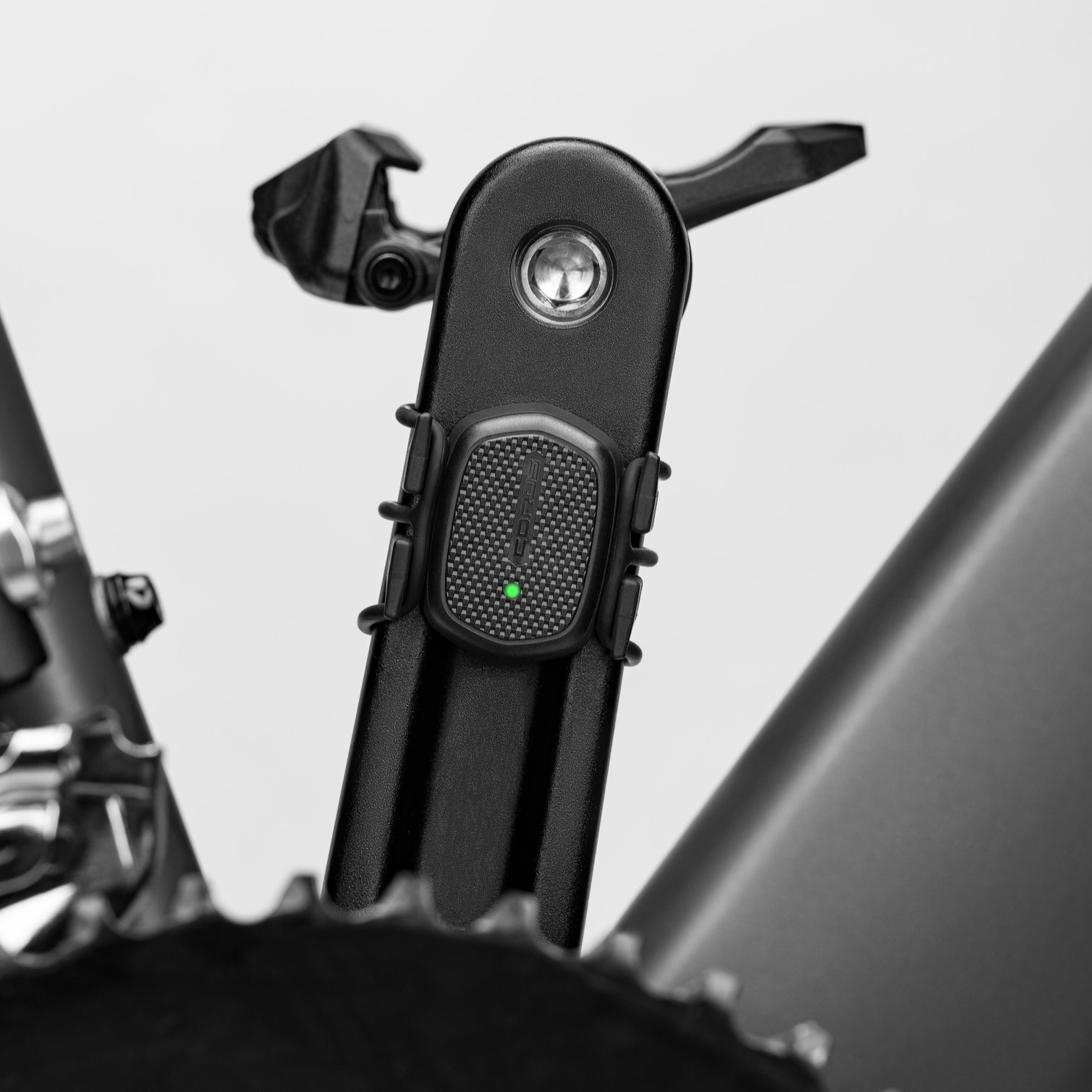 Close-up shot of a COROS bike cadence sensor mounted on a bike pedal.